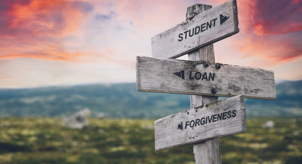 student loan forgiveness quote caption text written engraved on wooden signpost outdoors in nature with dramatic red skies.