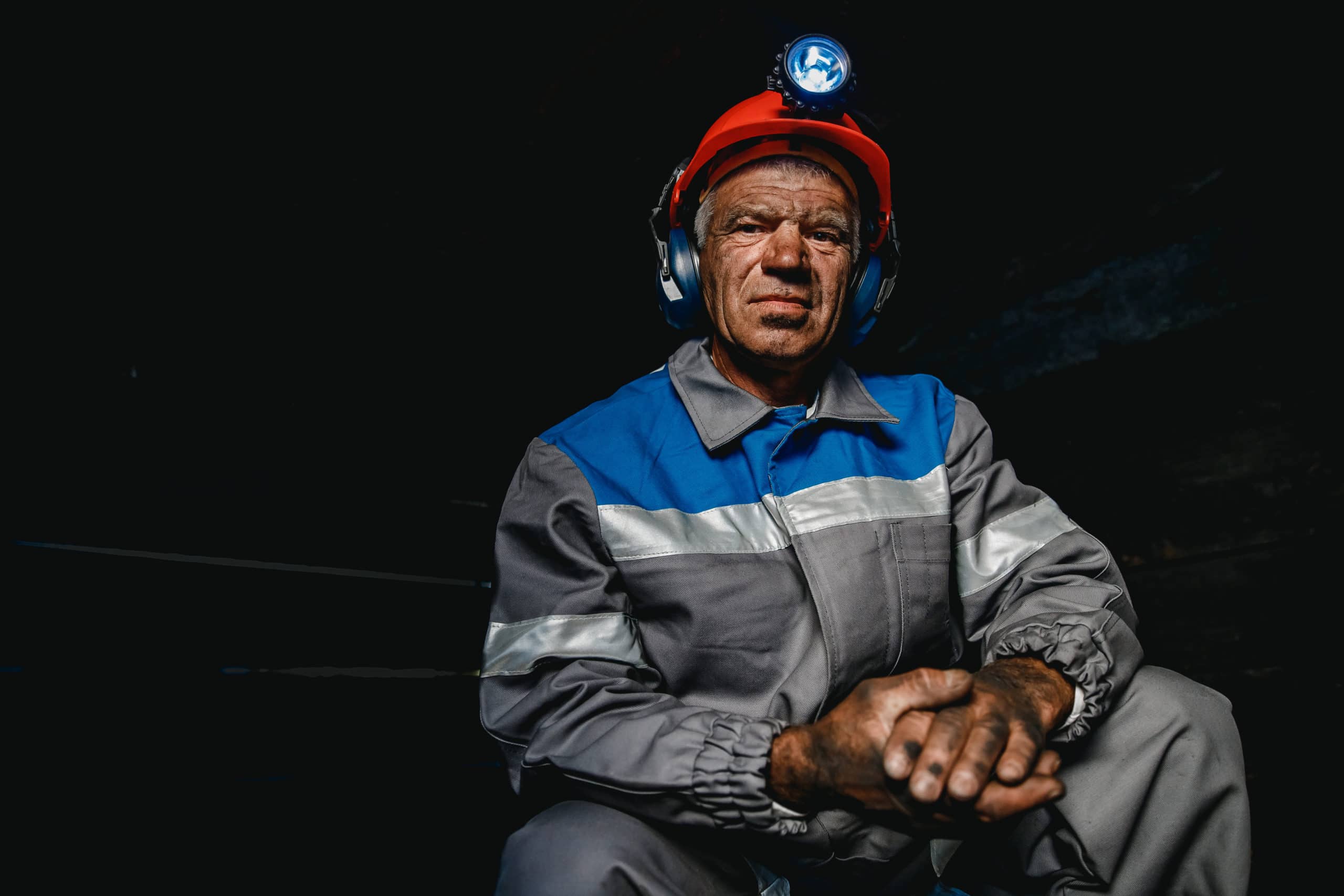 black lung benefits - Portrait miner coal man in helmet with lantern in underground mine. Concept industrial engineer.