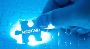 Medicaid benefits Health Care Concept. Doctor holding a jigsaw puzzle with MEDICAID word.