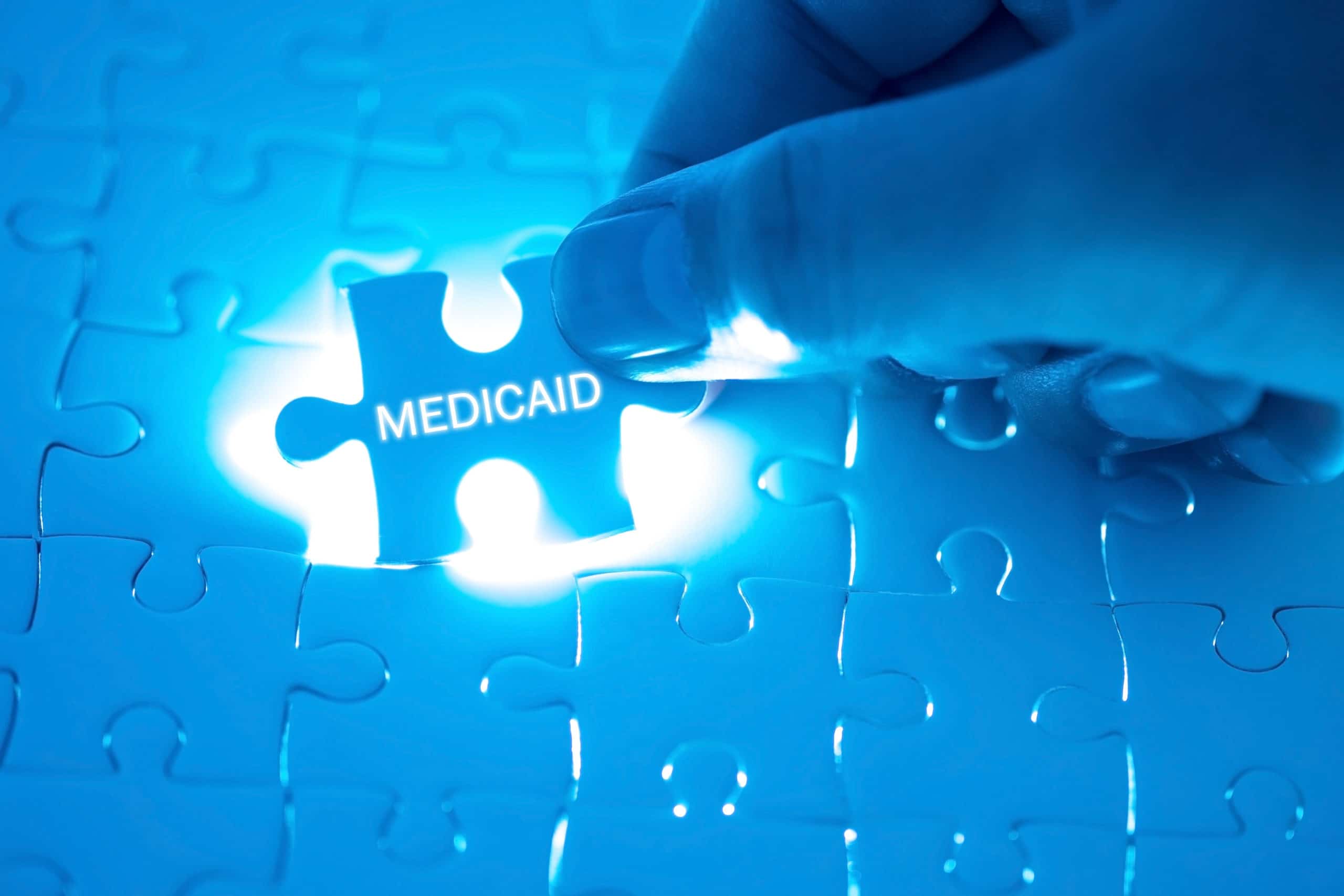 Medicaid benefits Health Care Concept. Doctor holding a jigsaw puzzle with MEDICAID word.