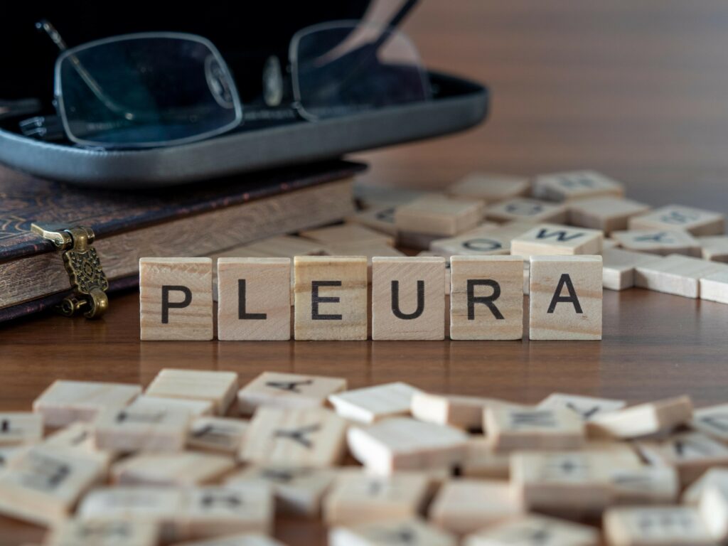 pleura cancer word or concept represented by wooden letter tiles on a wooden table with glasses and a book