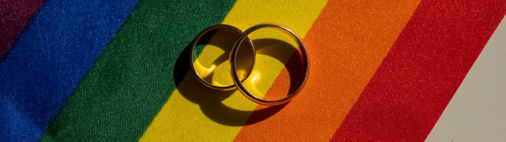 Legalization of same sex marriage and social security benefits. Rainbow flag and wedding rings