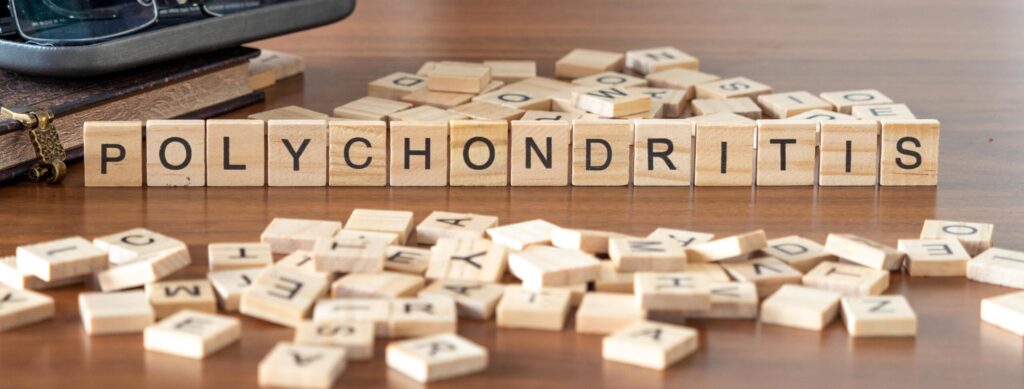 polychondritis word or concept represented by wooden letter tiles on a wooden table with glasses and a book